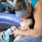 partner kisses birthing person in birthing pool