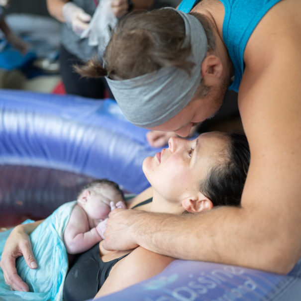partner kisses birthing person in birthing pool